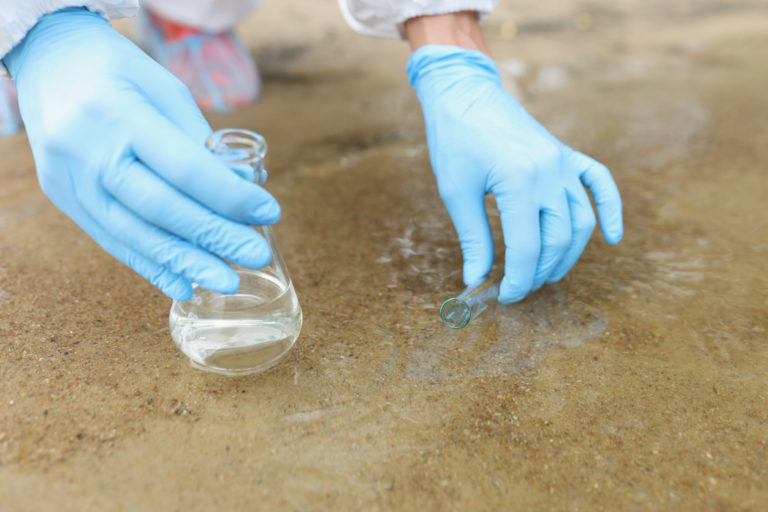 Scientist with gloves takes samples in pond. Water pollution in rivers and lakes concept